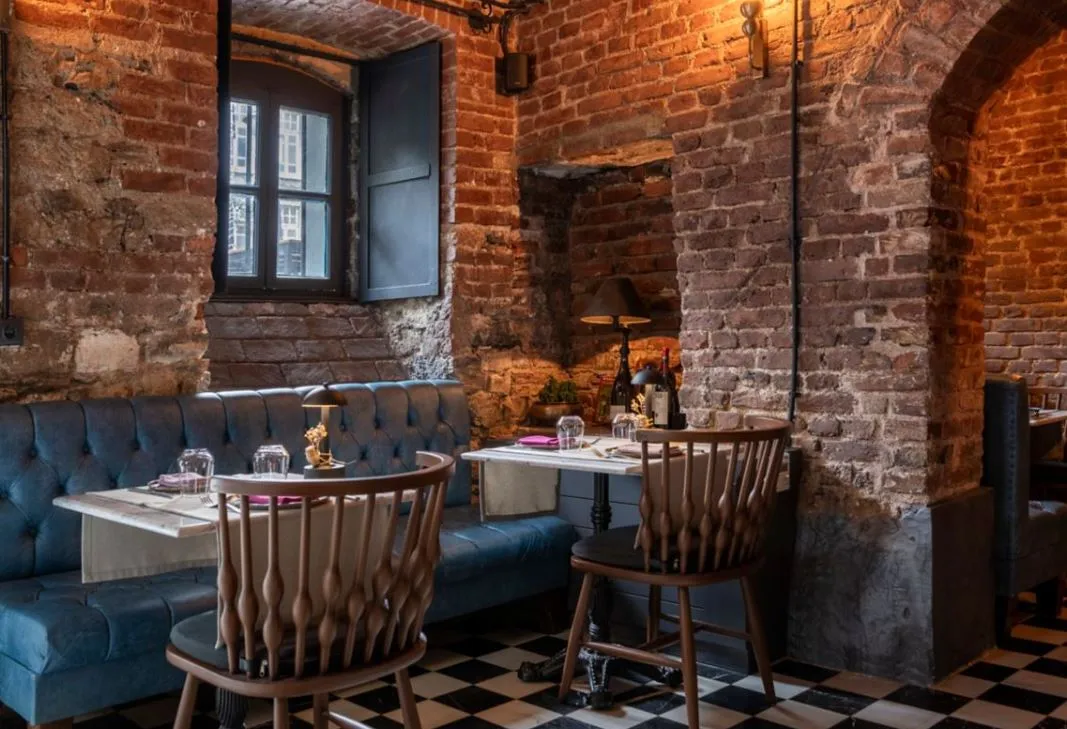 Tables and a blue banquette under the brick arches of Vigneron Wine House