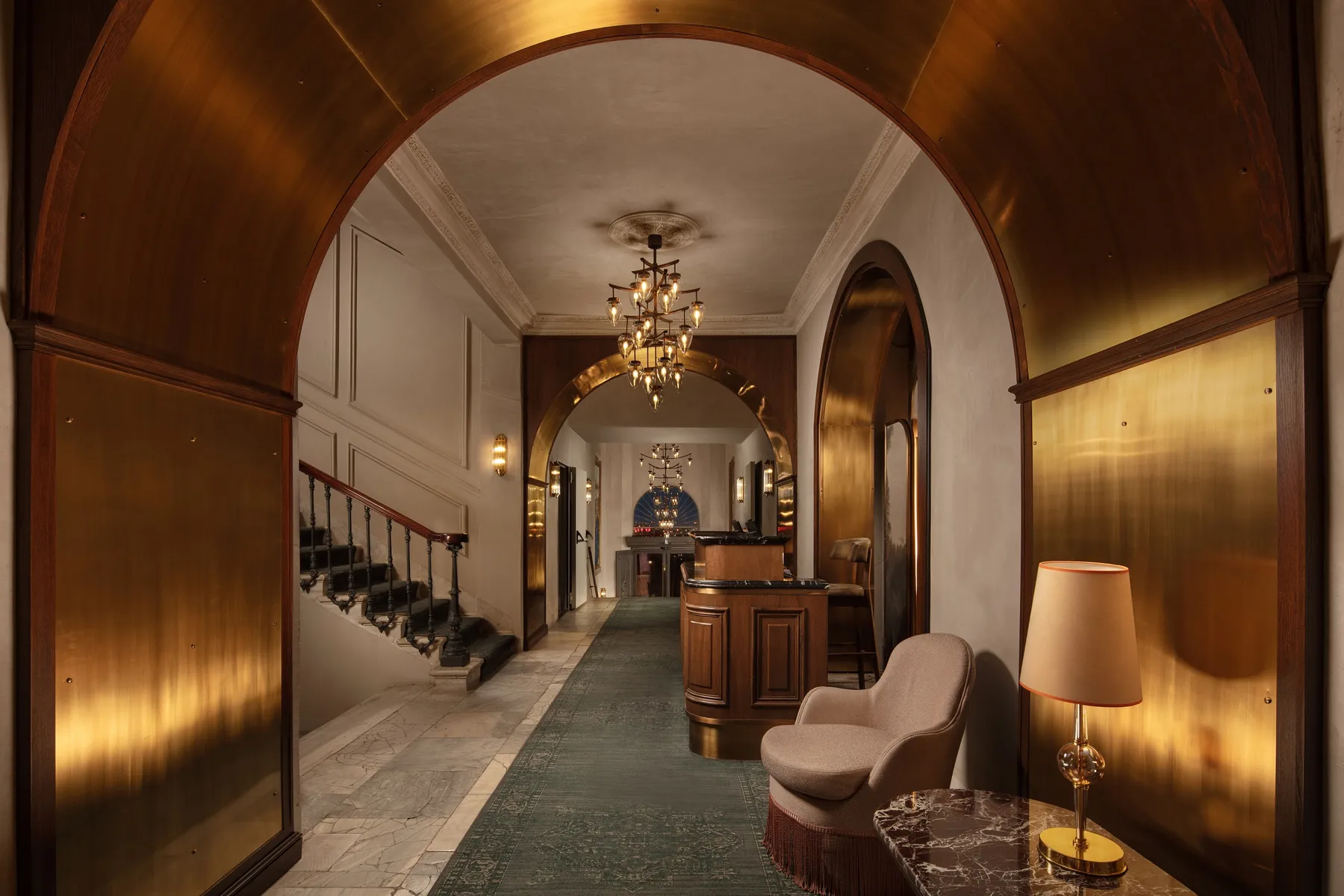 Arched entrance hall leading to the front desk under a chandelier